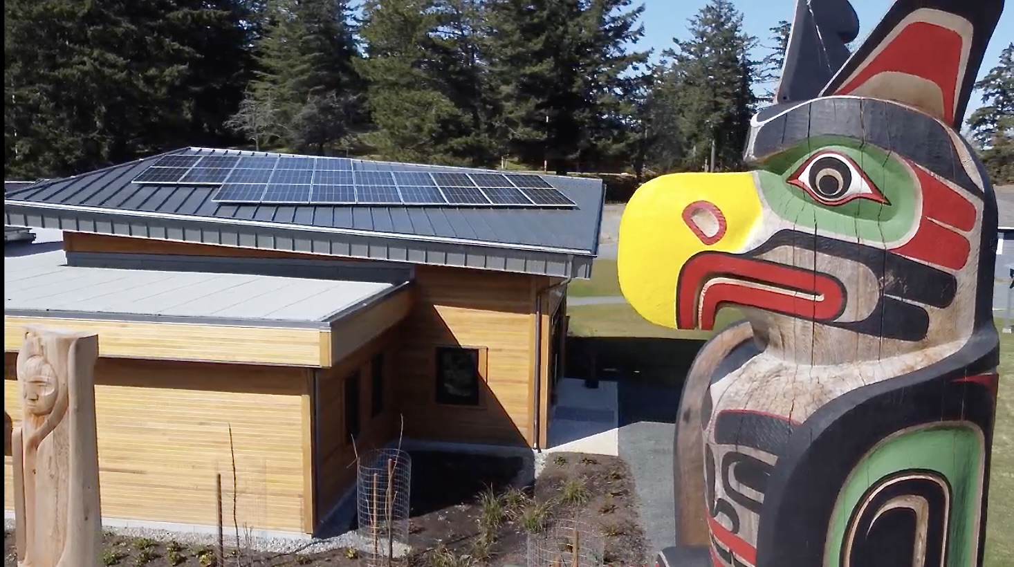 Solar array on the rooftop of a community building. There is a totem pole to the right, in the foreground of the image.
