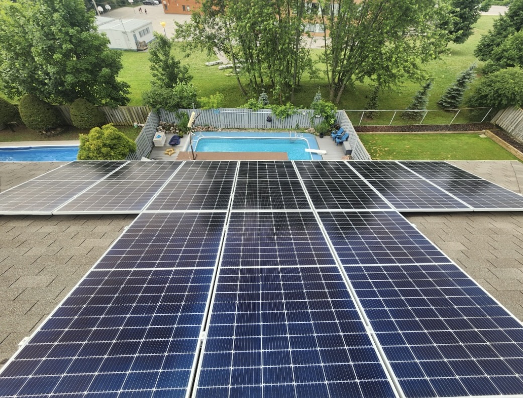 Roof top view of solar panels. Looking down, you can see the backyard of the home with a pool.