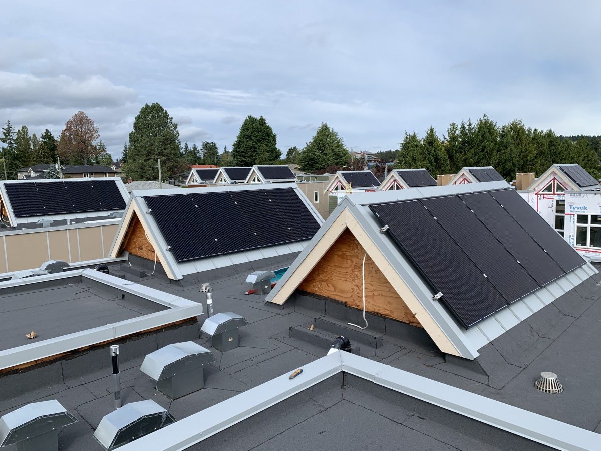 rooftop view from a series townhomes. There are solar panels installed on all the a-frame dormers on each roof.